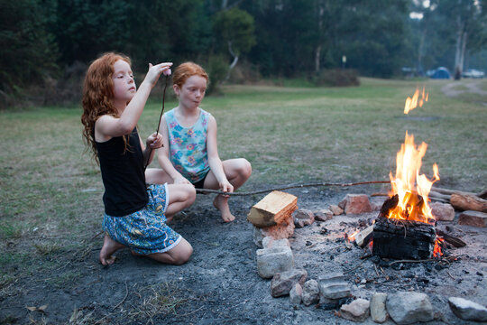Two girls toasting marshmallows on a campfire