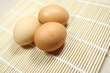 Fresh brown eggs arranged on a bamboo mat. Natural lighting and rustic setup make it ideal for food, kitchen, or organic farming-themed visuals