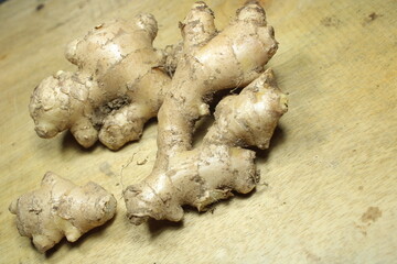 Fresh raw ginger roots with soil on the wooden table