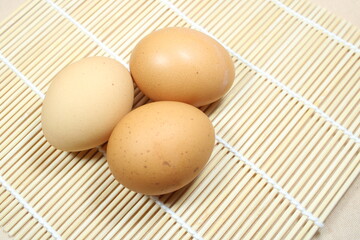 Fresh brown eggs arranged on a bamboo mat. Natural lighting and rustic setup make it ideal for food, kitchen, or organic farming-themed visuals