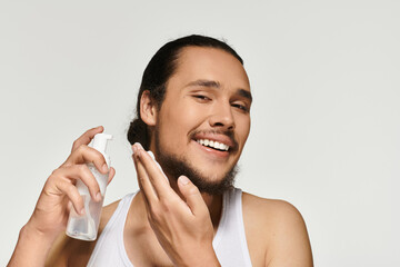 Young man applying skincare with a smile in a bright indoor setting