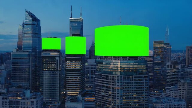 Modern urban city skyline at twilight with multiple green-screen billboards on high-rise buildings, aerial drone perspective, lit windows and city lights, chroma panels glowing