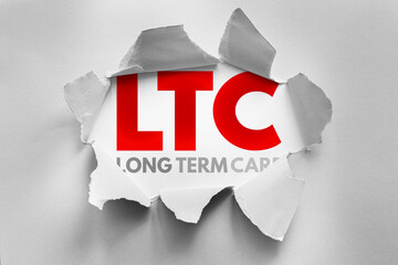 LTC acronym for Long Term Care shown behind torn paper. Healthcare and elder support concept,...
