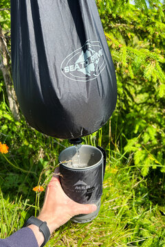 Close-up shot of camper using Sea to Summit water bag to pour water into MSR pot.