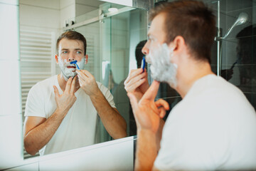 Young man shaving his beard