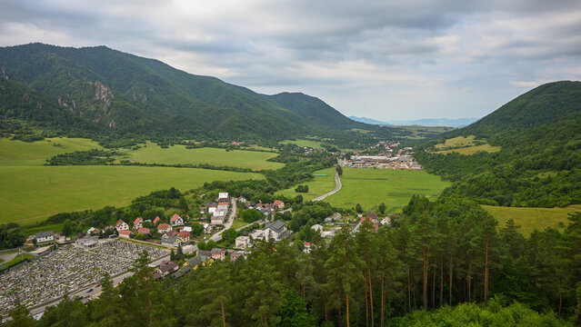 Scenic landscape showcasing the rajec valley in slovakia, featuring rolling hills, lush forests, and a charming village under a cloudy sky
