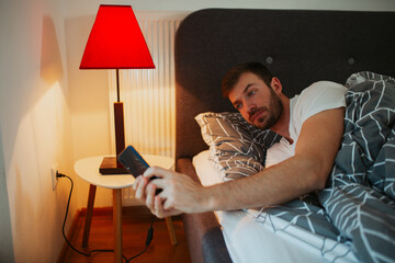 Man lying in the bed and scrolling before sleep