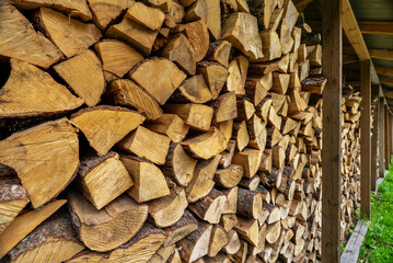 Stack of neatly chopped firewood in a wooden shed.