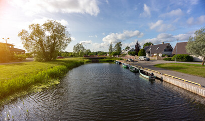 Calm river with moored boats, surrounded by greenery.
