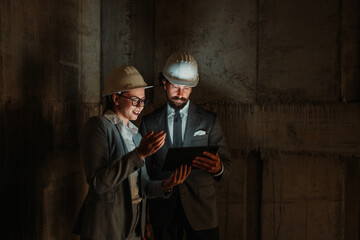 Architects using tablet in dark construction zone discussing project
