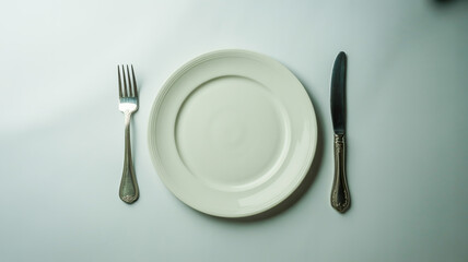 A minimalist photograph of an empty white ceramic dinner plate centered on a light gray background