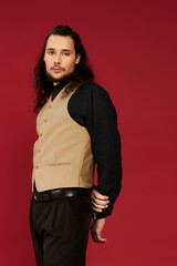 Charming bearded young man poses confidently against a bold red background, exuding style