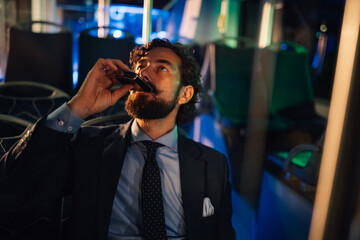 Elegant businessman drinking from flask on night bus ride