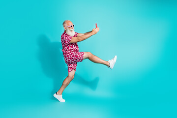 Obraz premium Full body photo of senior bearded man excited walk hold device dressed stylish pink leopard print clothes isolated on cyan color background
