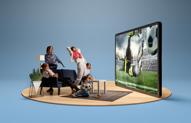 Family reacts emotionally to a goalkeeper diving save in a soccer match shown on large display in...