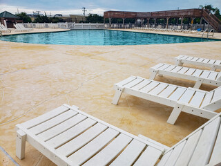 Empty Poolside with White Loungers and Blue Water