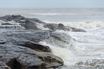 Waves crashing over the beach rocks, rocks and ocean with blurred motion of waves, rocky shoreline meeting coastal waters