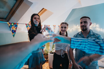 A group of friends or family celebrating a birthday at home, clinking glasses in a brightly...