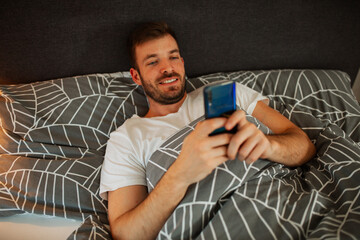 Man lying in the bed and scrolling before sleep