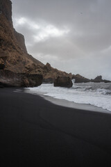 Dramatic landscape of black sand beach and cliffs and rocks by the sea