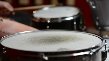 Drummer playing a rhytm on a drum kit. Selective focus image of drum kit being played on in a small home studio: floor tom close to the camera, snare drum and cymbals unfocused in the background.