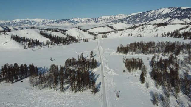 Drone footage of snowy mountains, valleys, and forests in Ust-Koksa, Altai Republic, Russia, under clear skies, showing the remote region&rsquo;s beauty during winter.