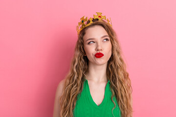 Confident young woman wearing a stylish crown posing against a pink background with playful expression