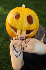 bare feet of a child and a carved orange pumpkin, with a Halloween smile. Preparing for Halloween....