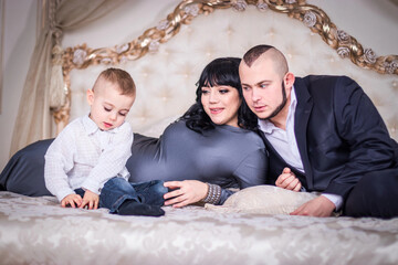 Dad and mom play with a son on the bed