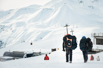 Two paragliding instructors walk together to gondola lift station to take customer to do...