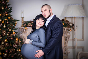 Happy pregnant couple hugging in room. Happy bride and groom are waiting for a baby.
