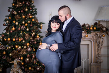 Happy pregnant couple hugging in room. Happy bride and groom are waiting for a baby.
