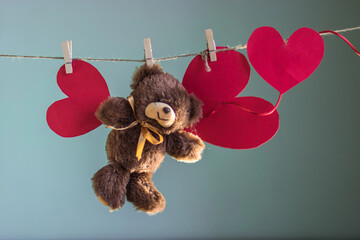 Toy Teddy bear with papers hearts are suspended from the rope clothespins on a background of...
