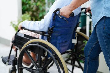 Caregiver help Asian elderly woman disability patient sitting on wheelchair in hospital.