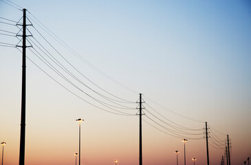 Powerlines and light poles against clear sky at dusk