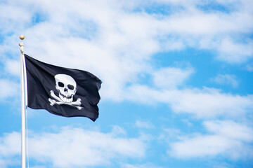 Pirate flag against sky with white clouds