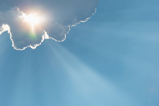 Sunlight shining through clouds against blue sky