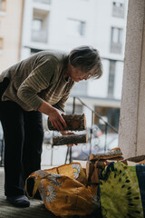 A senior woman adjusts firewood in a structured manner outside, expressing responsibility and...