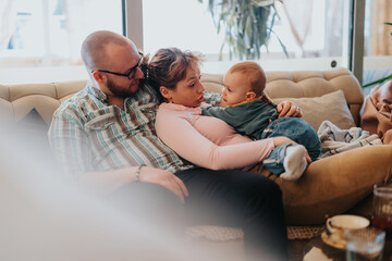 A bonding moment as parents share time with their baby in a comfortable and warm indoor setting,...