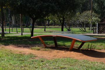 Naklejka premium Curved Teqball table in a public park, designed for soccer-style ball games using feet and head. Innovative outdoor sports equipment for recreational training and fun in green urban spaces.