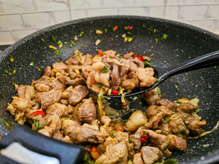 Cooking pork with spices, chili peppers, garlic and onions in traditional style
