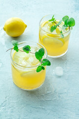 Glasses of lemonade with fresh mint, a mocktail with lemon juice, on a blue background, summer cold...