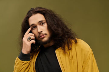 Charming young man with curly hair and beard striking a thoughtful pose in an artistic setting
