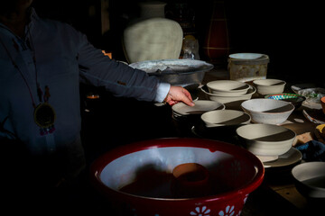 A woman checks unfinished and unpainted ceramics in her workshop at a pottery and ceramics workshop, Samarkand, Uzbekistan