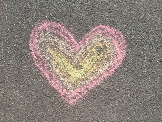 Children's drawing in colored chalks on the pavement, a colorful heart. Children's street art. Horizontal photo. Hand-drawn artwork, top view.