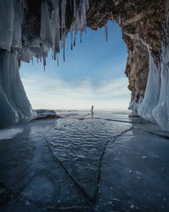 Person walking on a frozen lake from an icy cave.