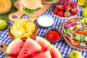 Summer picnic or BBQ brunch or lunch background, tasty barbecue table with hamburgers, salads,...