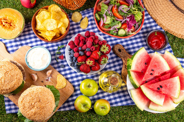 Summer picnic or BBQ brunch or lunch background, tasty barbecue table with hamburgers, salads,...