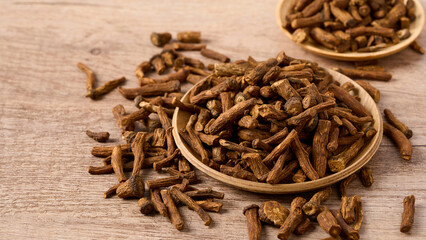 closeup pile of dry dandelion root herb for loose tea in wood bowl on wooden table background with copy space