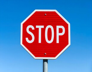 Red stop sign against a clear blue sky, signaling caution and traffic control.